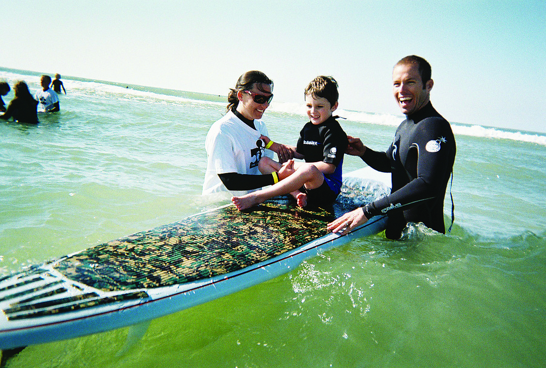 Dylan Wojcik with volunteer Michelle Chrzczonowski and surfing instructor Jacob Shields