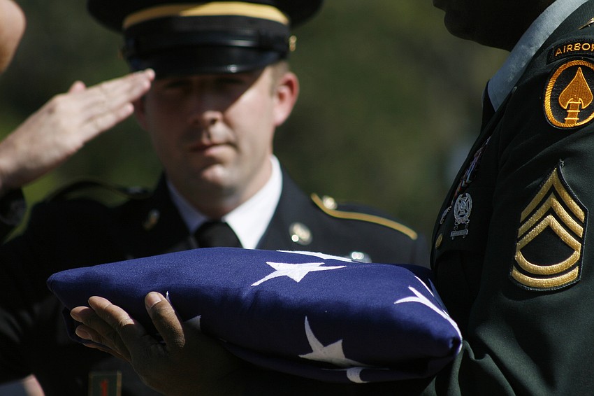Staff Sgt. Lyle Allen salutes the memorial flag as his wife, Ashley, sang the national anthem.