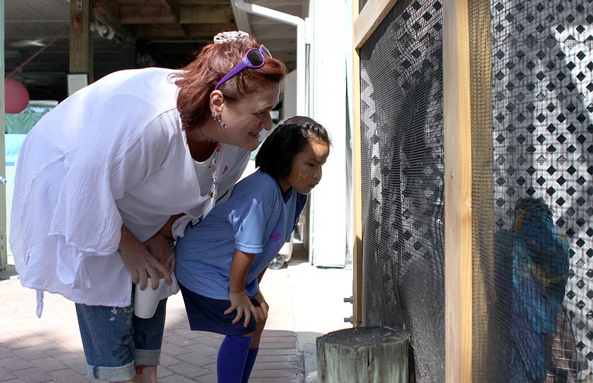 Sue Stearns and her daughter, Hannah Rudo, talk to Gangi the parrot while they attend the second birthday party for Save Our Seabirds.