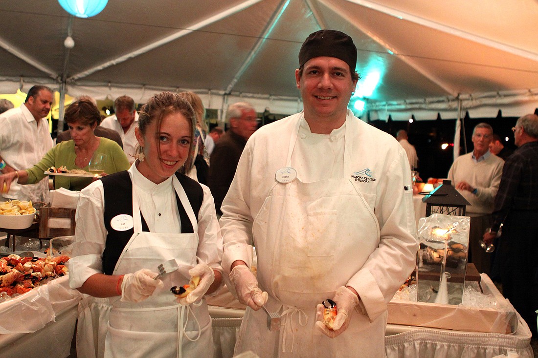 Kat Bouchard and Blake Halverson hold up some stone crab legs from their work table during the Wine & Stone Crab Celebration.
