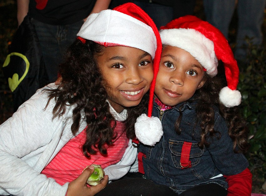 Solenia and Taiz Caminero wear Santa hats as they watch the parade on Saturday.