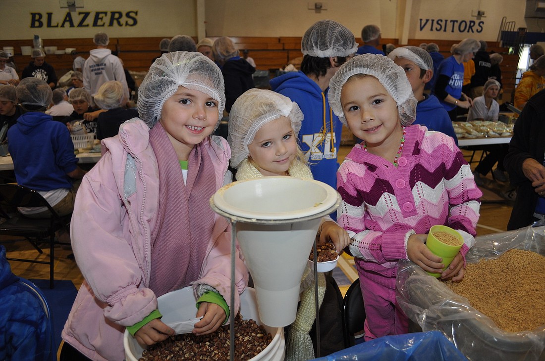 Preschoolers Summer Roland, Isabela Taylor and Katelyn Moffitt pack meals for hungry families.