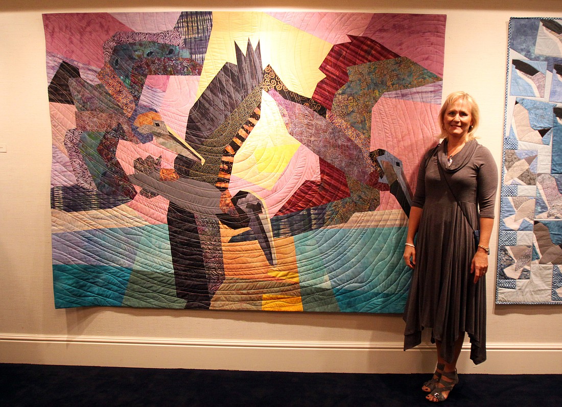 Janine Ward poses next to her newest quilt Ã¢â‚¬Å“Brown PelicansÃ¢â‚¬Â during the art opening featuring her quilts at Bird Key Yacht Club.