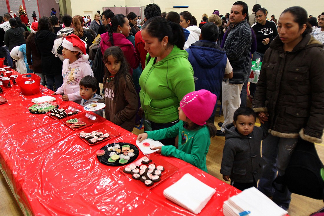 Children and their parents line up for cookies and juice at the annual holiday party put on by Healthy Families Sarasota.