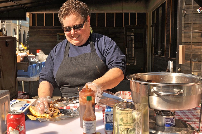 Nancy Krohngold dishes up a pulled pork sandwich and baked beans during lunch time at the restaurant's future site, at 301 Pineapple Ave.