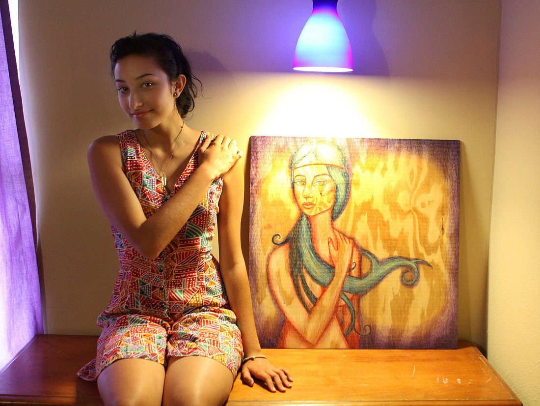 Briana Calderon mimics the pose of the woman she painted on this wooden canvas.
