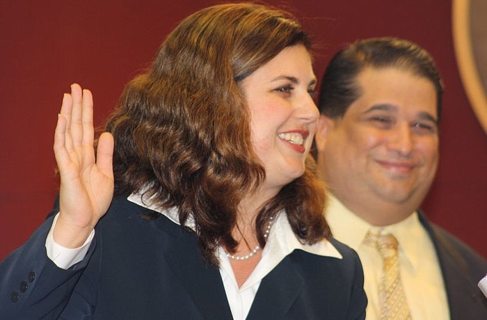 Newly appointed County Commissioner Christine Robinson takes the oath of office, with her husband, Eric, by her side.