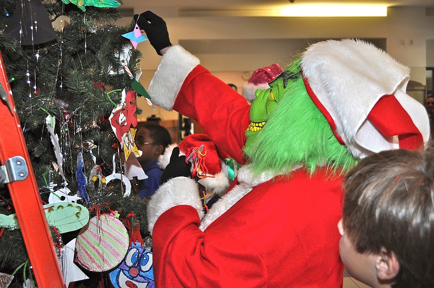 The Grinch (Ann White) decorates the Christmas tree at the Sarasota Courthouse.