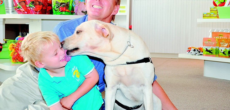 Max Pettingell gets a slobbery kiss from Daphne, a Southeastern Guide Dog in training, while visiting the organization's new downtown Sarasota Discovery Center in September with his father, Roger, a Southeastern Guide Dog Board member.