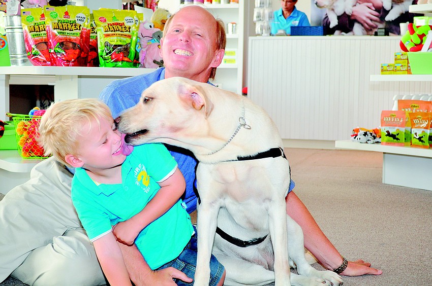 Max Pettingell gets a slobbery kiss from Daphne, a Southeastern Guide Dog in training, while visiting the organization's new downtown Sarasota Discovery Center in September with his father, Roger, a Southeastern Guide Dog Board member.