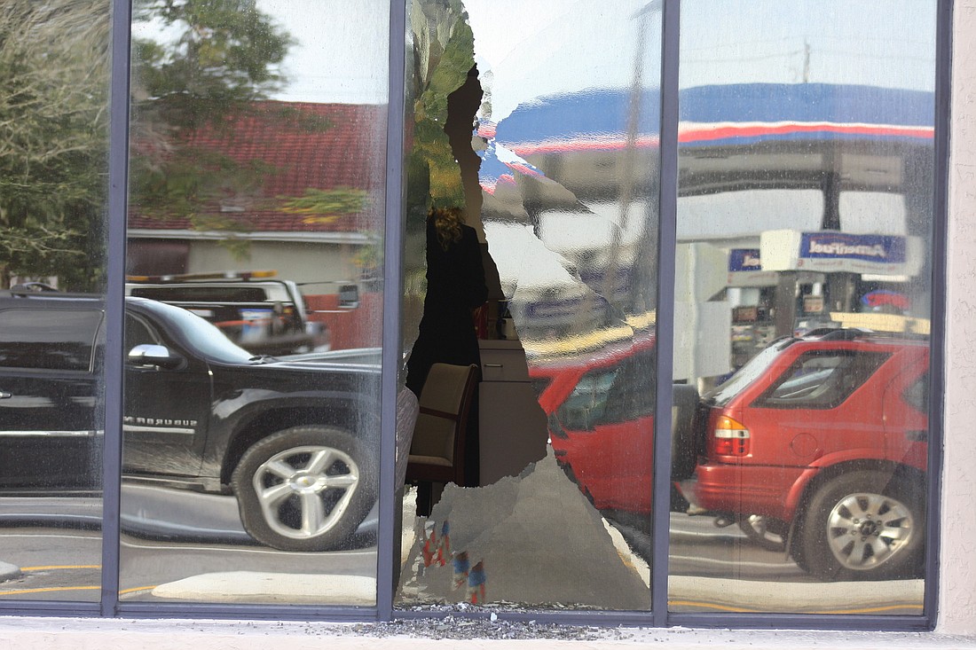 A bank employee makes a cup of coffee just inside a window that was broken over the weekend.