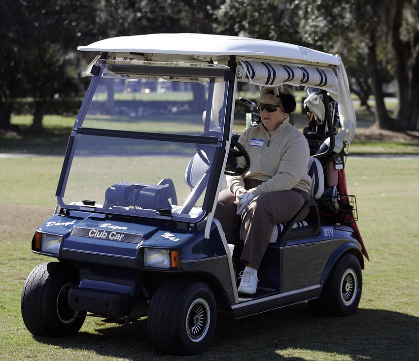 Daryl Bayer attempts to stay warm while her teammates tee off.