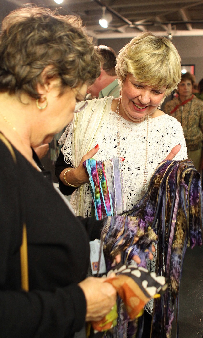 Kathie Hayes shows off her scarves to Susan Kennedy on Thursday, Feb. 10 at the opening night of the Fabulous Arts Boutique.