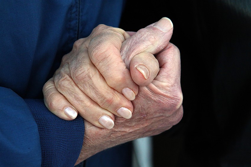 An elderly couple hold hands during the Say I Do, Again ceremony, Monday, Feb. 14 on Siesta Key Beach.