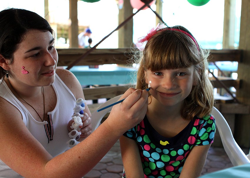 Samantha Sexe paints a swan onto Zoe Newell's, 6, face during the second birthday party for Save Our Seabirds.
