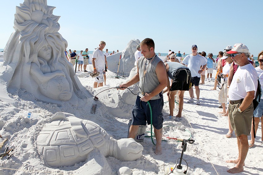 Sean Fitzpatrick sprays some water onto part of the sand sculpture 