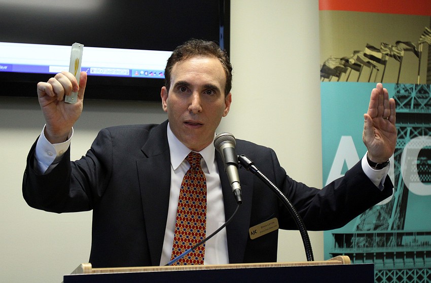 Brian Lipton shows off the mezuzah, donated by the Sieglers, which was placed at the front entryway of the new office Thursday evening after a few quick speeches. Lipton referred to the mezuzah as the â€œJewish security systemâ€.
