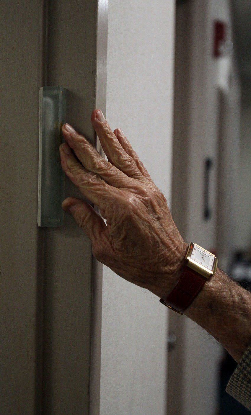 Nate Benderson places the mezuzah on the entryway of the new AJC office inside the Bank of America Building Thursday evening.