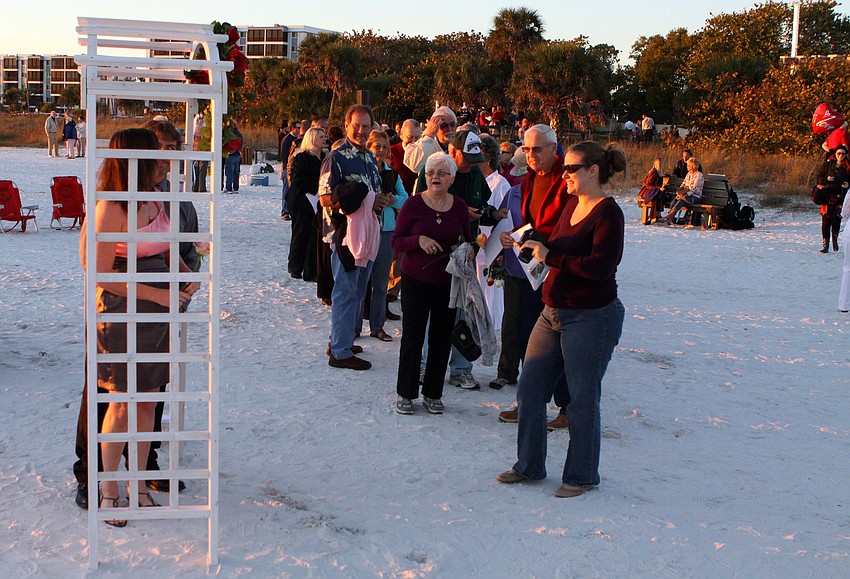 People line up to get a photo under a trellis on the beach during the Say I Do, Again ceremony, Monday, Feb. 14 on Siesta Key Beach.