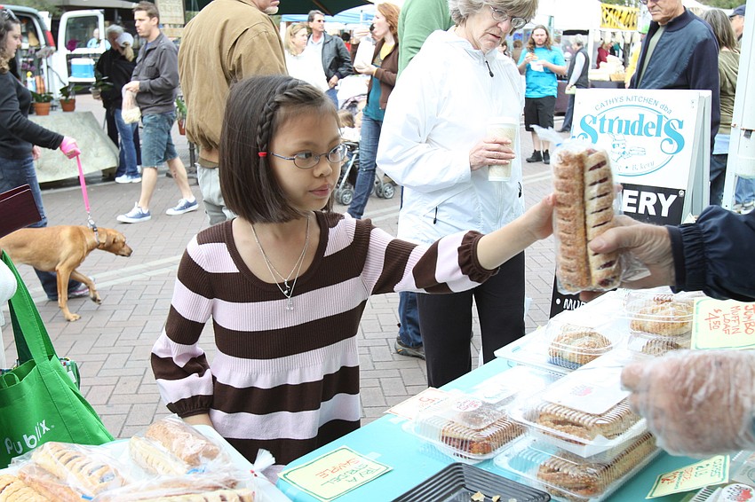 Erin Chen, 9, takes her baked goods that she bought for herself at Strudel's stand at the farmers market on Saturday, Jan. 22.