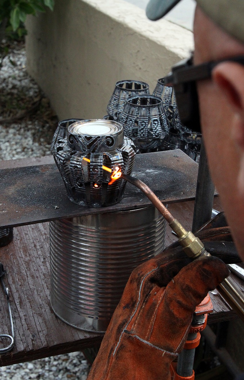 Leslie Dawley of Aloe Tinnery, creates decorative candle holders out of tin cans during the 17th annual Siesta Key Craft Festival Saturday, Feb. 5, in Siesta Key Village.