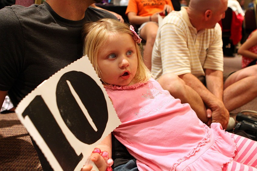 Ava Lenerz, 2 1/2, holds up a sign with a 