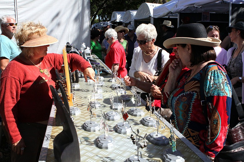People attending the art festival look at the jewelry created by Florida Fusion.