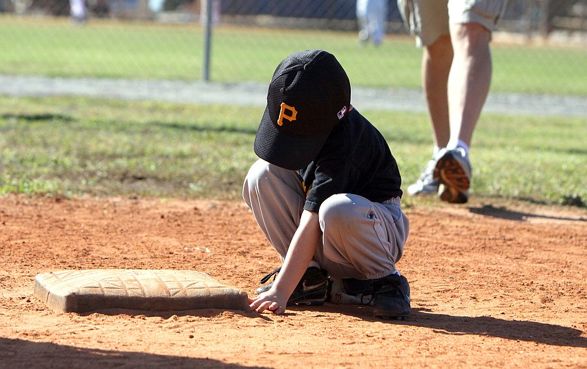 A Pirates player plays in the dirt between innings.