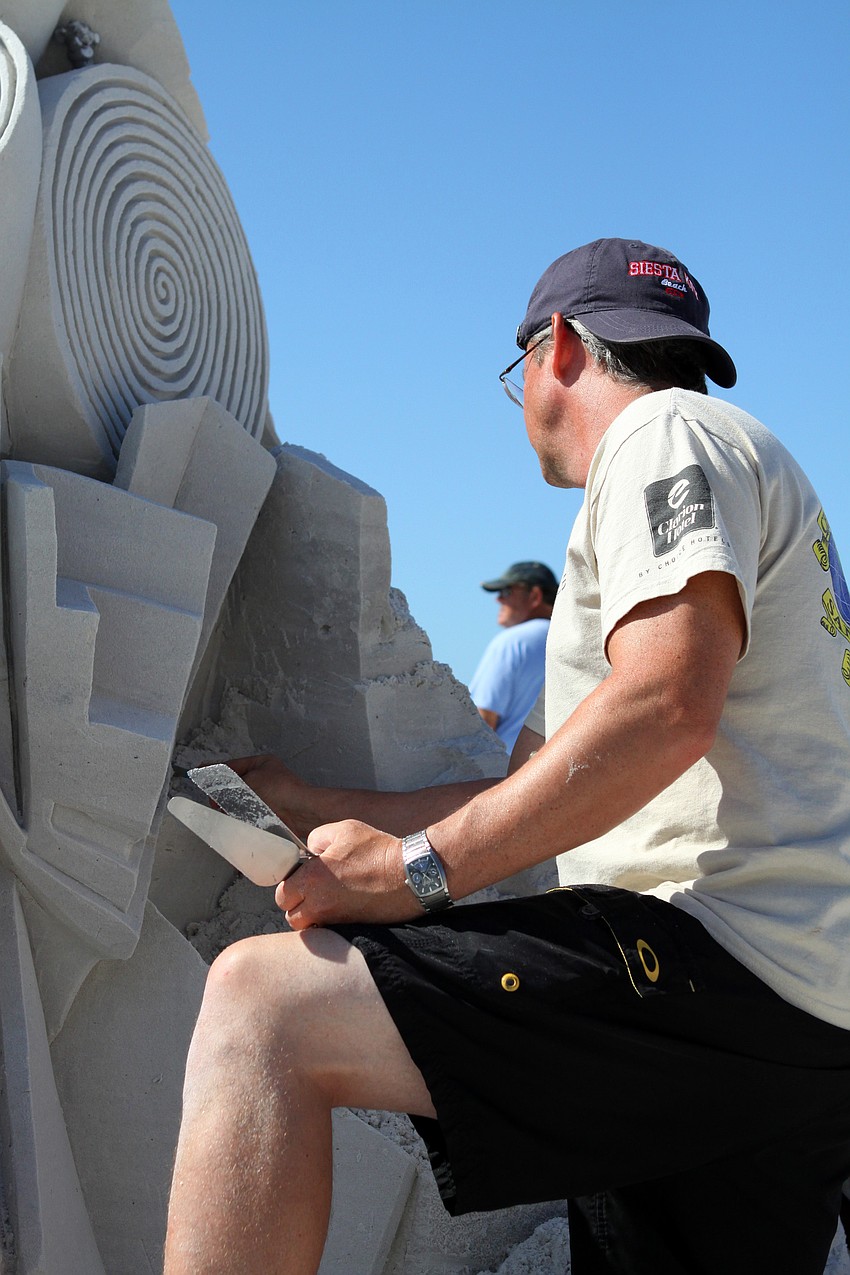 Fred Mallett does some repair work on his sand sculpture.