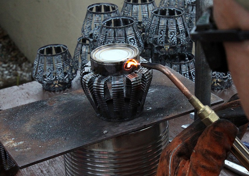 Leslie Dawley of Aloe Tinnery, creates decorative candle holders out of tin cans during the 17th annual Siesta Key Craft Festival Saturday, Feb. 5, in Siesta Key Village.