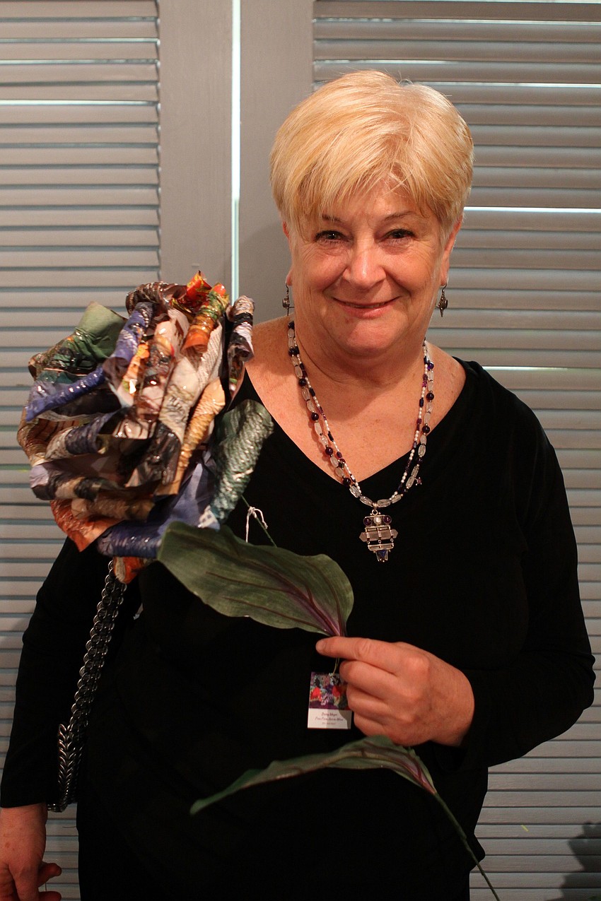 Artist Betsey Meyer with one of her magazine flowers on Thursday, Feb. 10 at the Fabulous Arts Boutique.