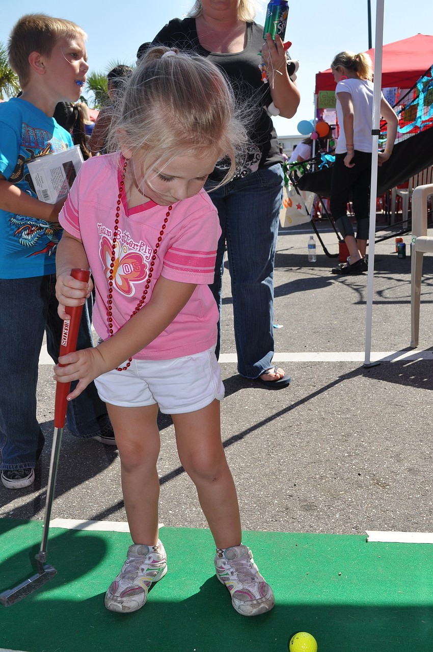Savannah Murray, age 4, takes a swing at the miniature golf booth.