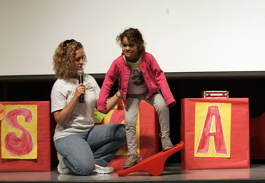 Five-year-old Ana Florez shows of her balancing skills with a little help from guidance counselor Sherri Brunner.