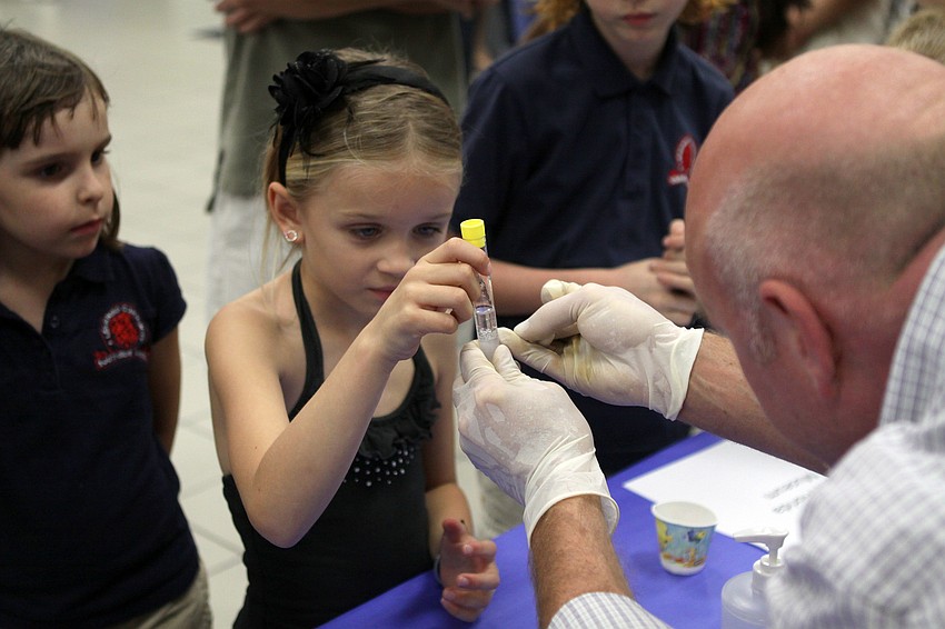 Jeff Rodgers helps Ava Riser, 7, with seeing her DNA in a test tube at the South Florida Museum table on Friday, Feb. 25 at Southside Elementary's Science Night.