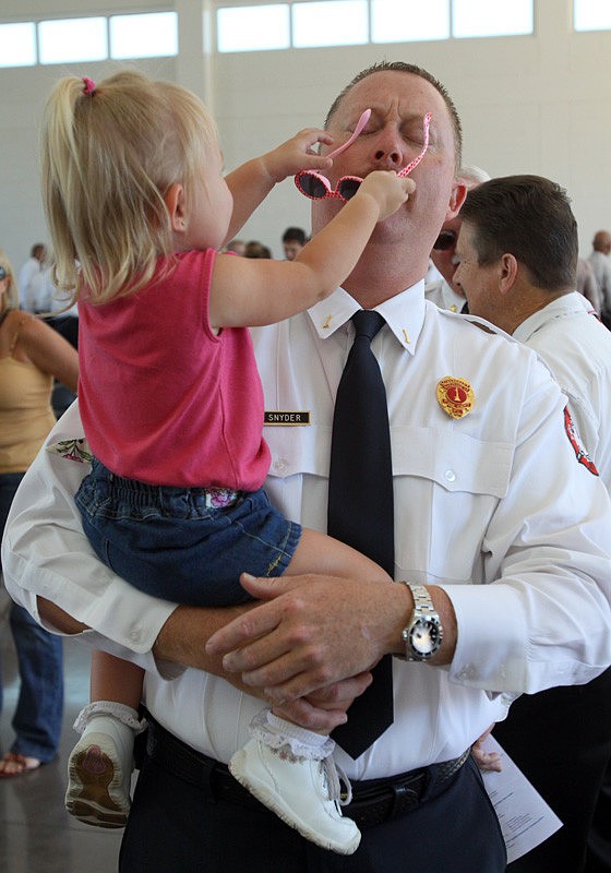 Peyton Snyder, 20 months, tries to place her sunglasses onto her father's, Lt. Glenn Snyder, face after the ribbon-cutting ceremony at Fire Rescue Station No. 1.