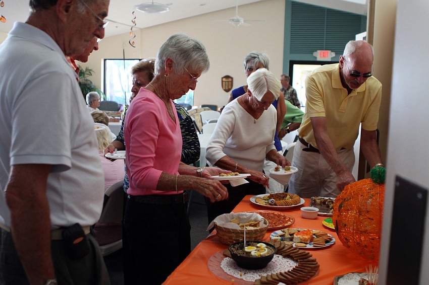 People get themselves some food that other residents brought to the potluck at Seaplace.