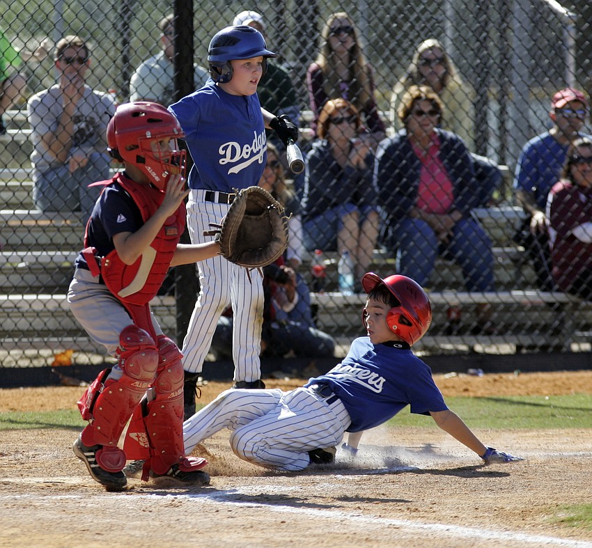 Nine-year-old Miles Kaitz slides safely into home plate, scoring a run for the Dodgers.
