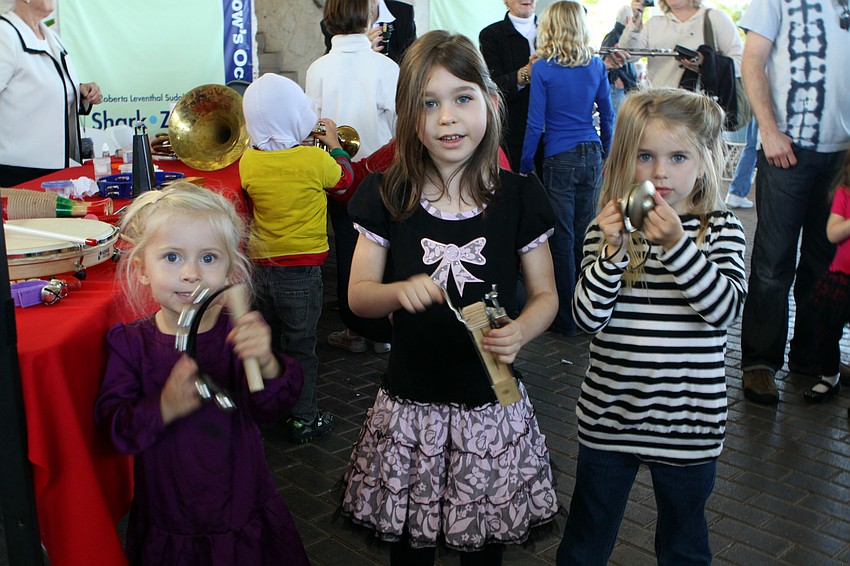 Morgan Hale, Sophia Pasold and Ava Morris try out some instruments at the â€œinstrument petting zooâ€ prior to the holiday concert at Mote.