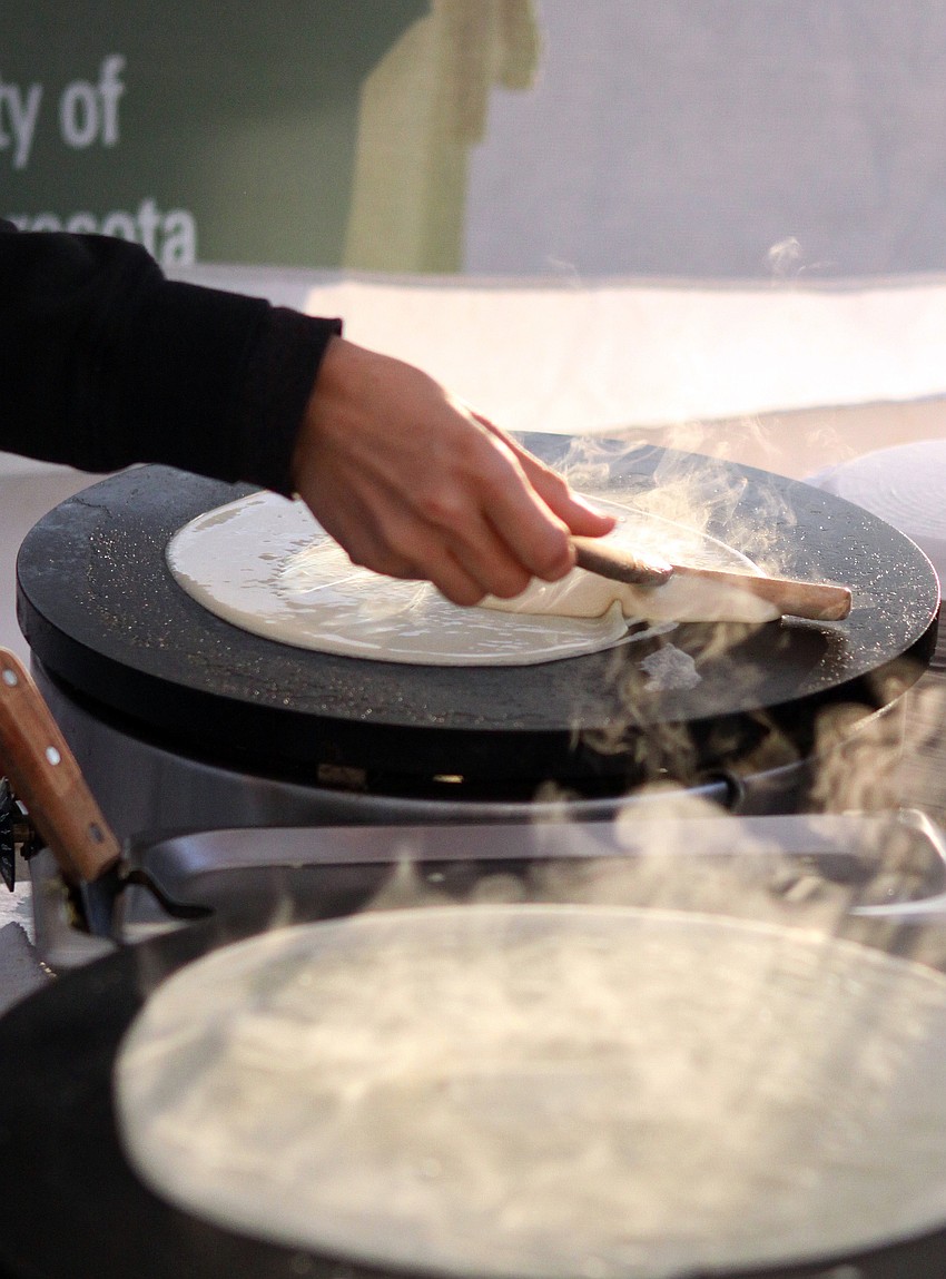 Natalia Winn works on making fresh crepes at Roverta's Crazy Crepes stand Saturday morning prior to the mad rush that the stand gets later on in the day at the farmers market.