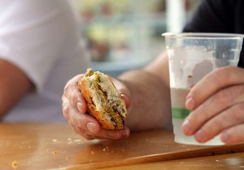 Dr. Patrick Dower holds his tie-breaker veggie burger in one hand and a glass of water in the other during Veg's First Annual Veggie Burger Eating Contest on Saturday, Feb. 5 outside of Veg. Dr. Dower was the winner of the eating contest.