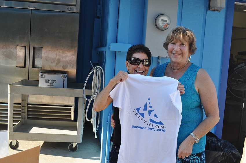 Susan Landau and Jackie Salvino hold up a Longboat Key Triathlon T-shirt.