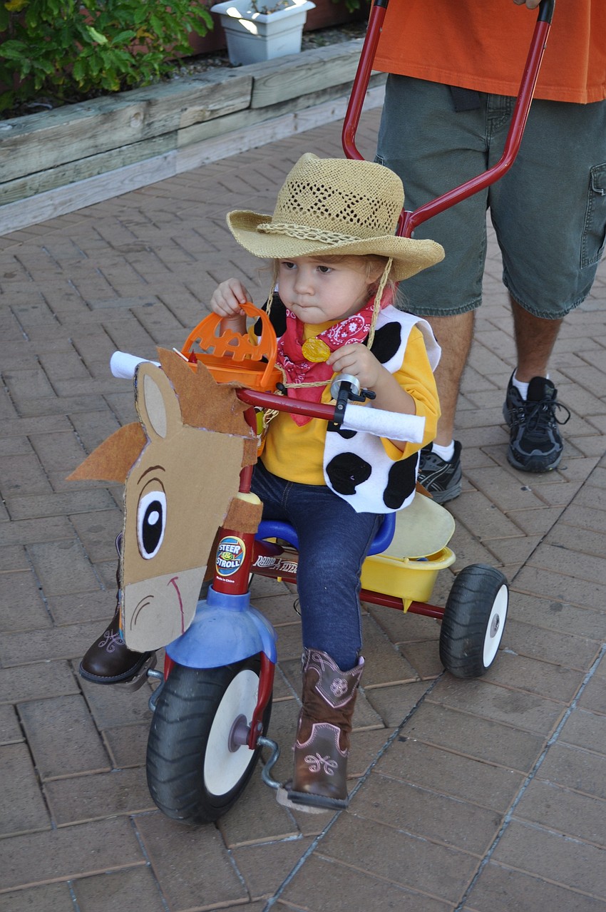 Lena Grace rolls down the street in cowboy costume.