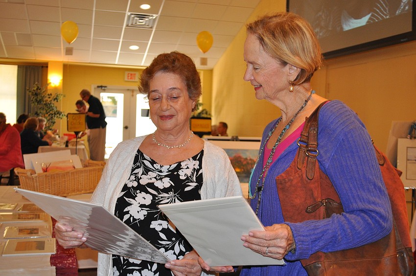 Joanna Cleary and Penny Hendry peruse artwork made by watercolor students at St. Boniface.