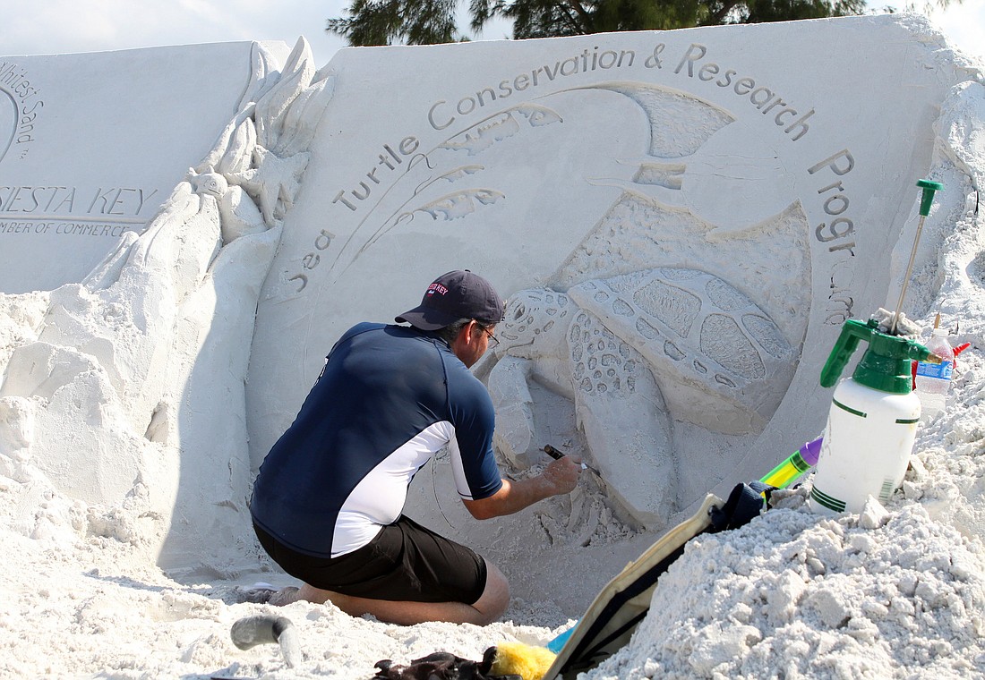 Sean Fitzpatrick puts the finishing touches on the turtles he has sculpted out of sand.