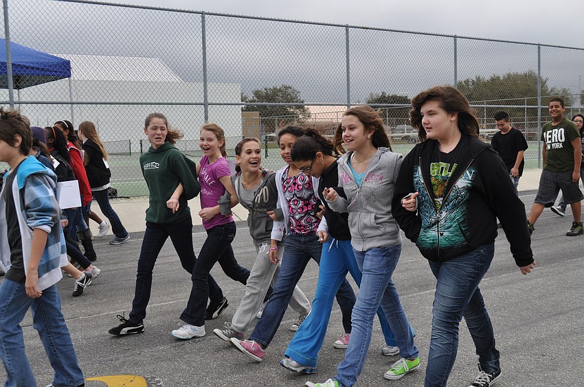 Students walk around the track arm-in-arm.
