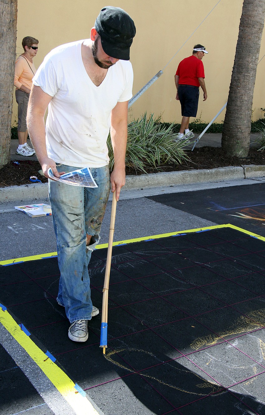Truman Adams uses a stick with a piece of chalk connected to the end of it to create his chalk masterpiece.
