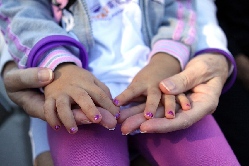 Diane Fritschle, a pancreatic cancer patient, holds the hands of her granddaughter, Hailey Fritschle, 2, whose fingers were painted with sparkly, purple fingernail polish for the walk.