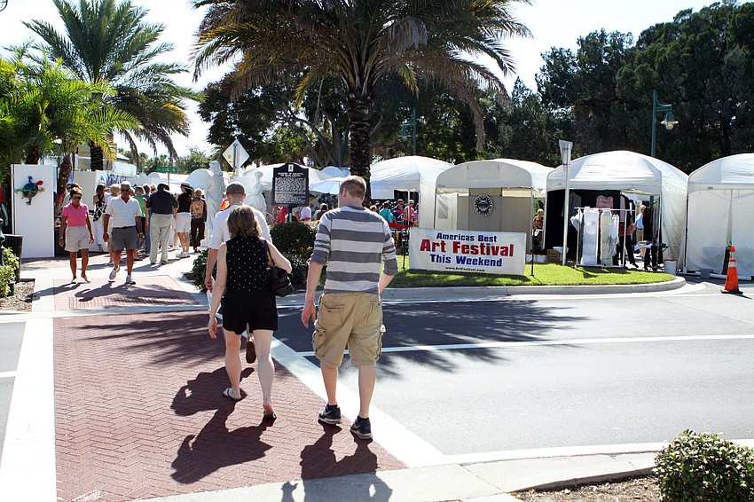 People cross the street to make their way over to St. Armands Circle to attend the 21st annual St. Armands Art Festival.