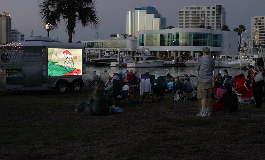 Children watch â€œHow the Grinch Stole Christmasâ€ on a large screen before the boat parade arrives at Bayfront Parade.