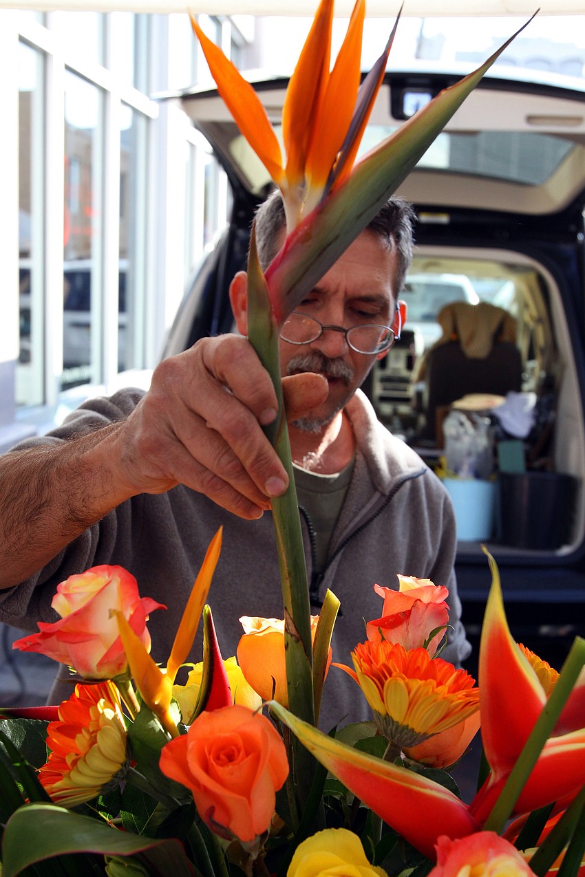 Michael Olivero adds the finishing touch to a beautiful flower arrangment at the farmers market on Saturday, Jan. 22. Olivero is one of the two guys who make up The Flower Guys booth.